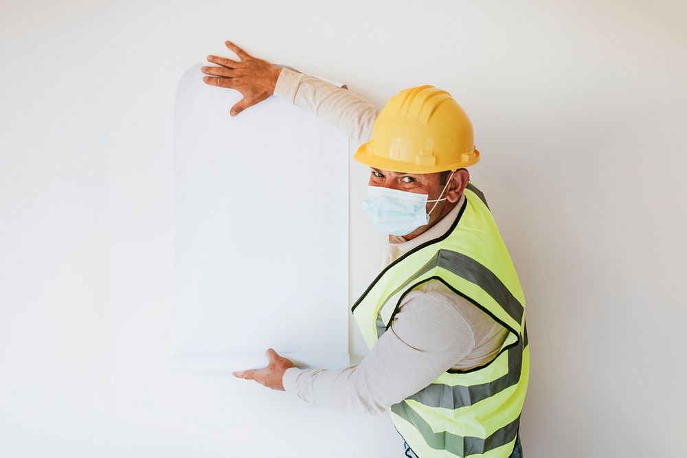 Blank paper on the wall and contractor wearing a mask