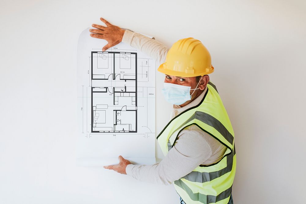 Contractor sticking floor plan on white wall