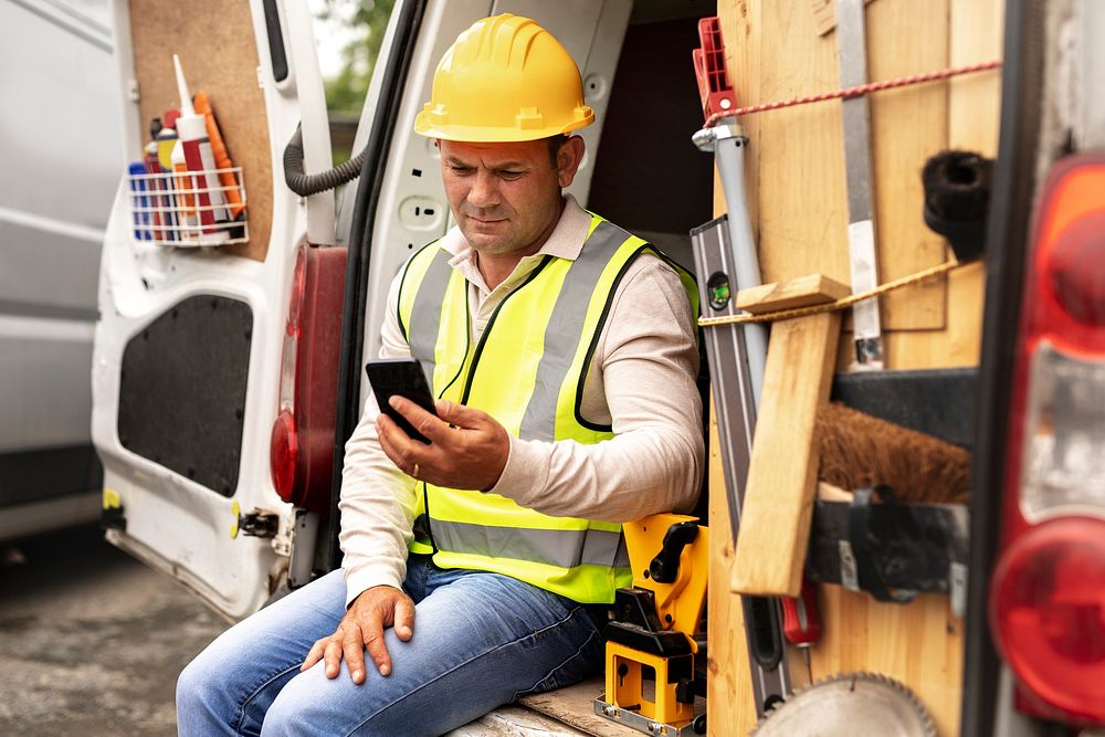 Construction worker using smartphone near the site 