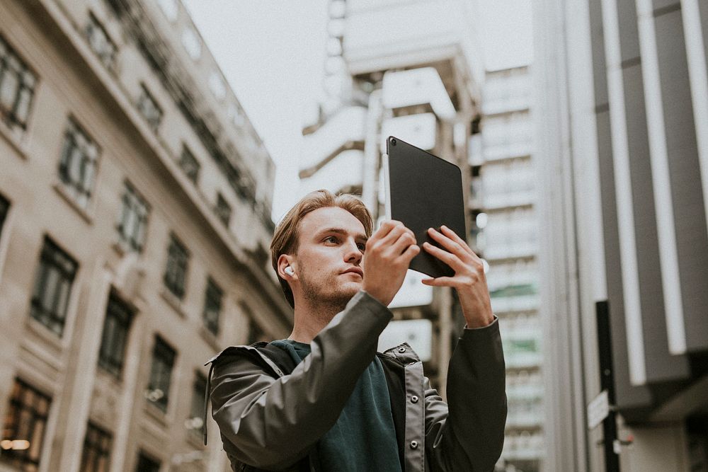 Man having a video call on his digital tablet in a city 