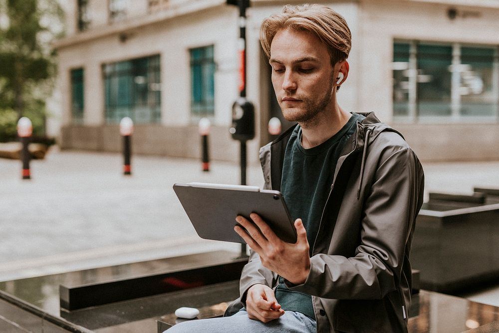 Man sitting and using a digital tablet in the city 