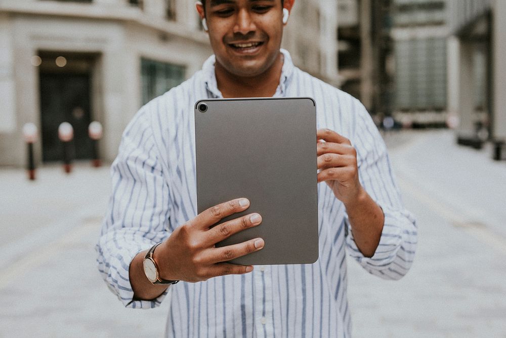 Man having a video call on his digital tablet in a city 