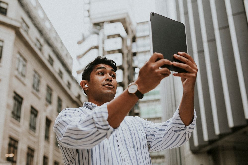 Man having a video call on his digital tablet in a city 