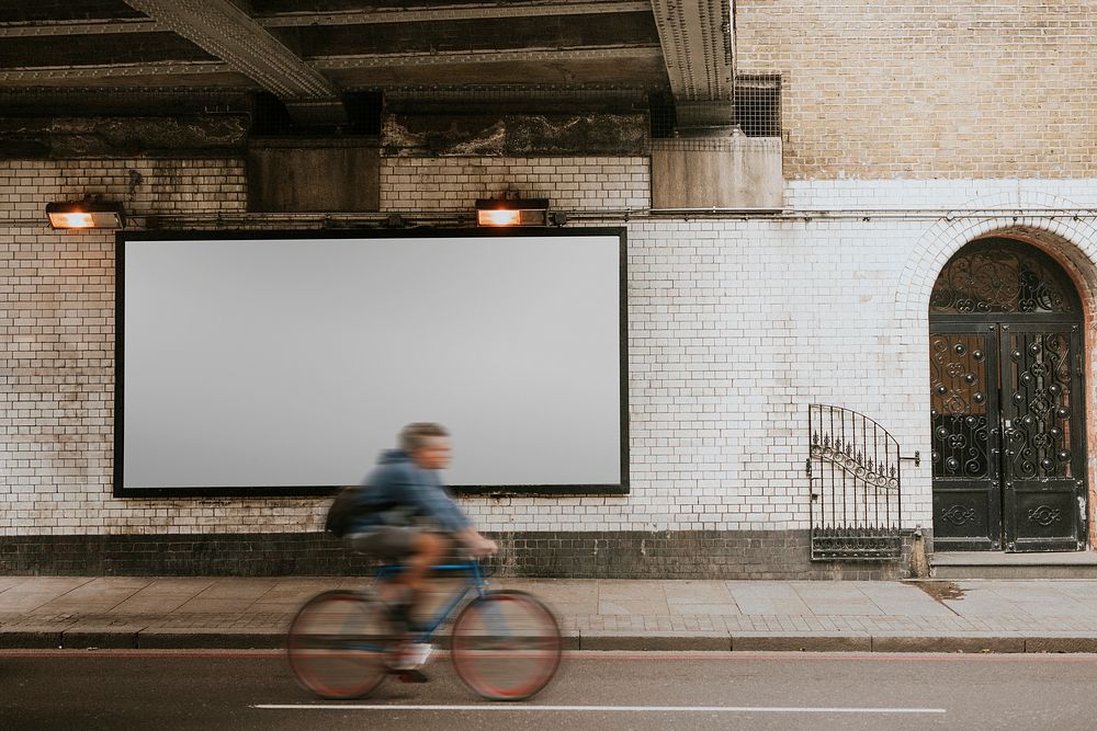 Biker biking past billboard with design space on the street of London