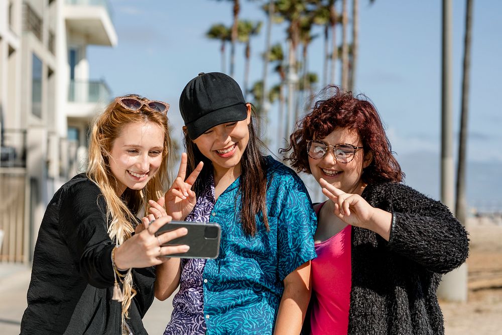 Teen girls taking selfie, enjoying summer together in Venice Beach, Los Angeles
