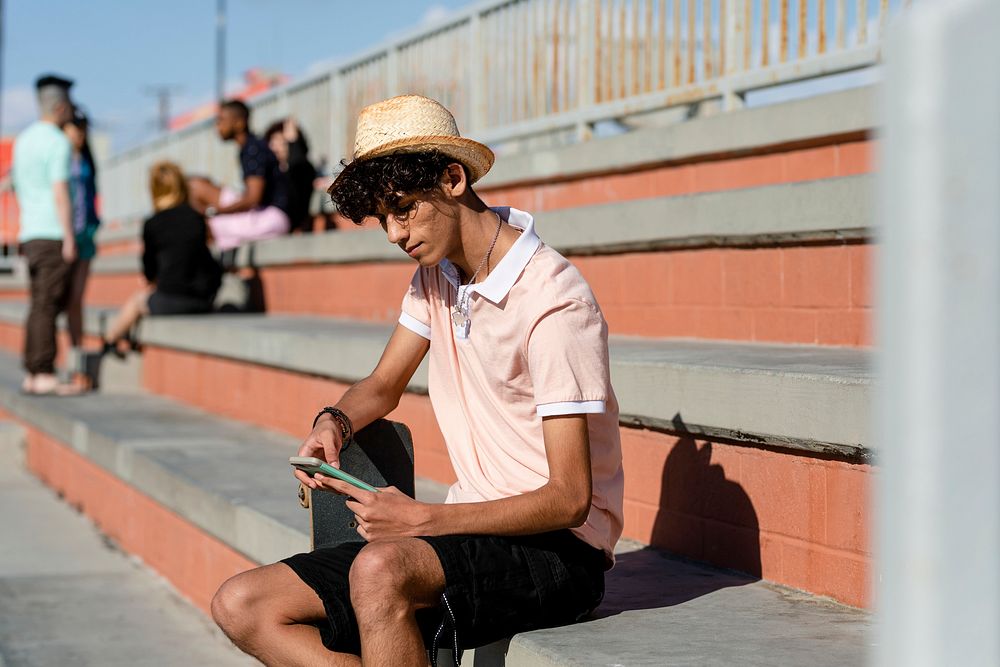 Teen boy adult listen to music, at a skatepark in summer