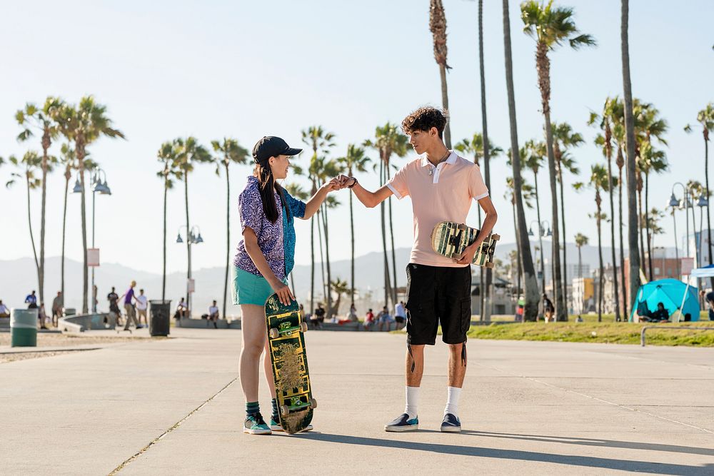 Friends fist bump, skaters at Venice Beach, Los Angeles