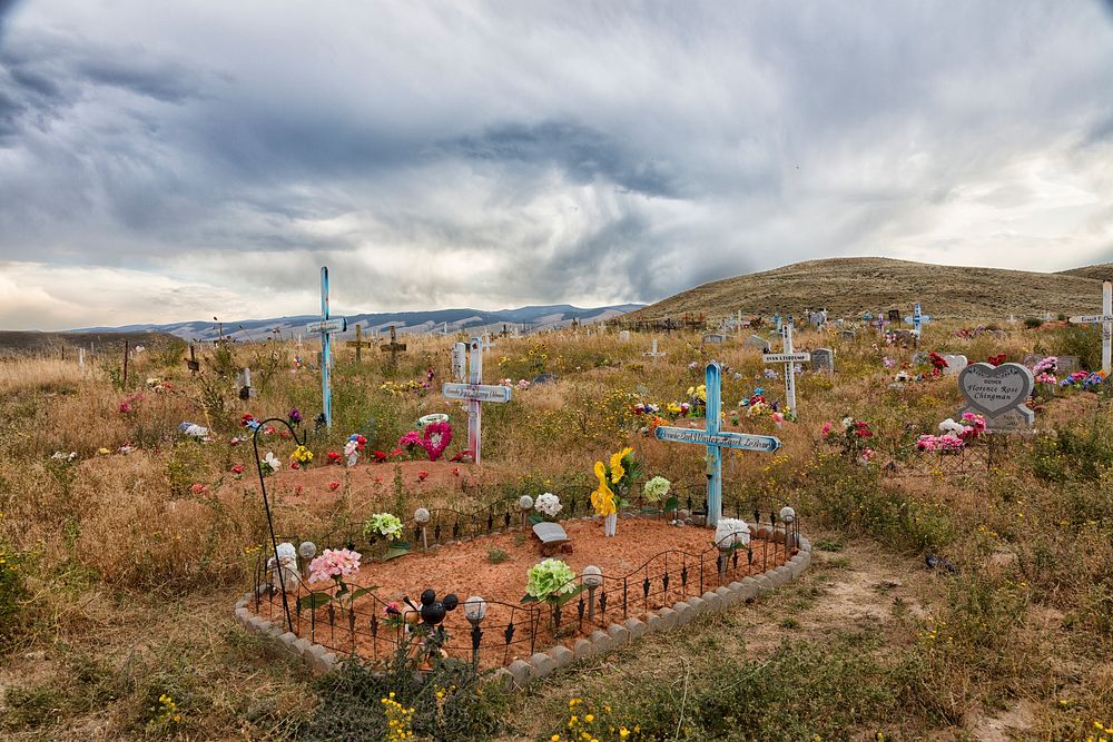 The humble, artistic Shoshone Tribal Cemetery spreads across the undulating prairie outside the town of Fort Washakie…