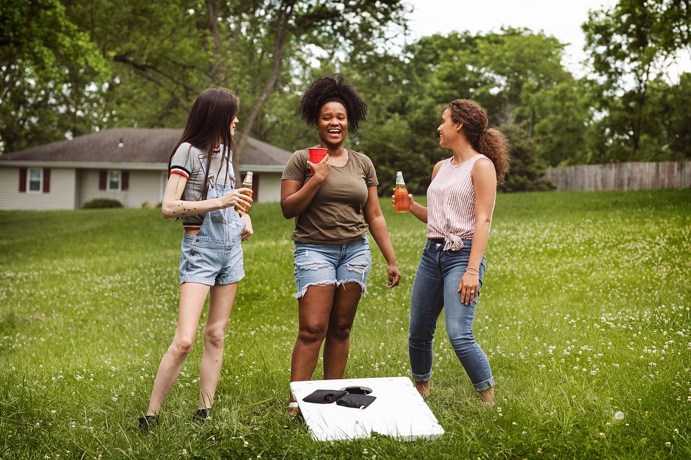 Women chatting during a cornhole game in the park
