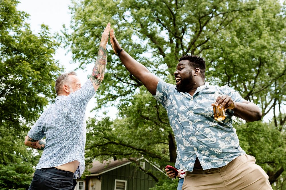 Two guys giving each other a high five at a summer party
