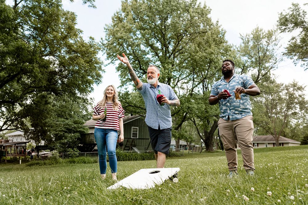 Friends playing cornhole at a summer party in the park