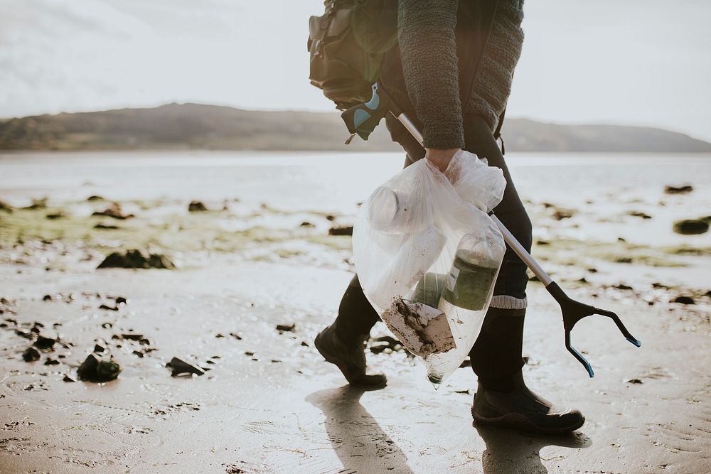 Beach cleanup volunteer carrying garbage bag for environment campaign