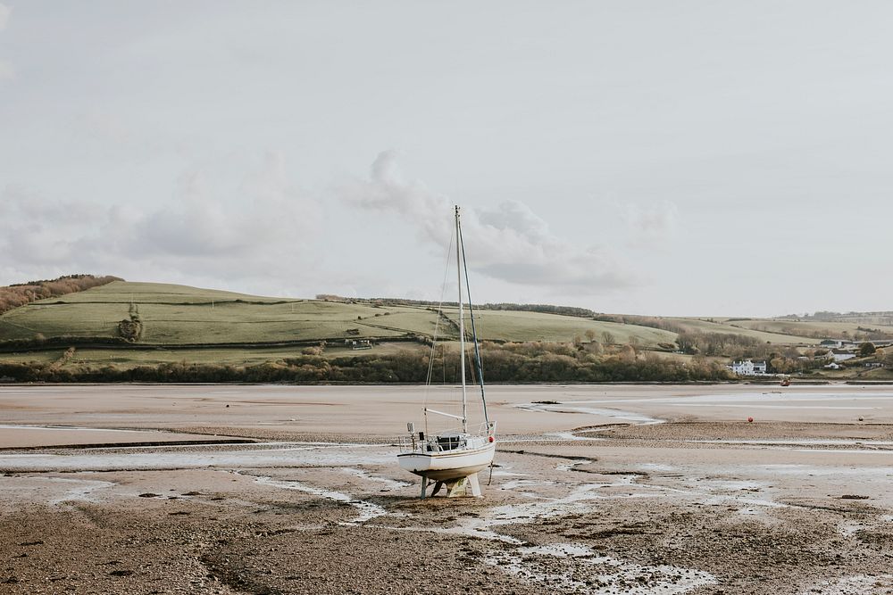 Sailboat stranded on a beach during ebb, Wales, UK