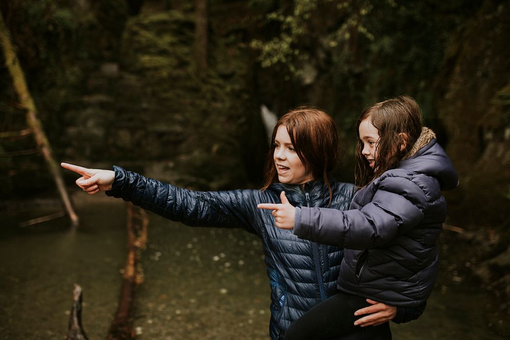 Family camping trip mother holding daughter in her arms while pointing their fingers