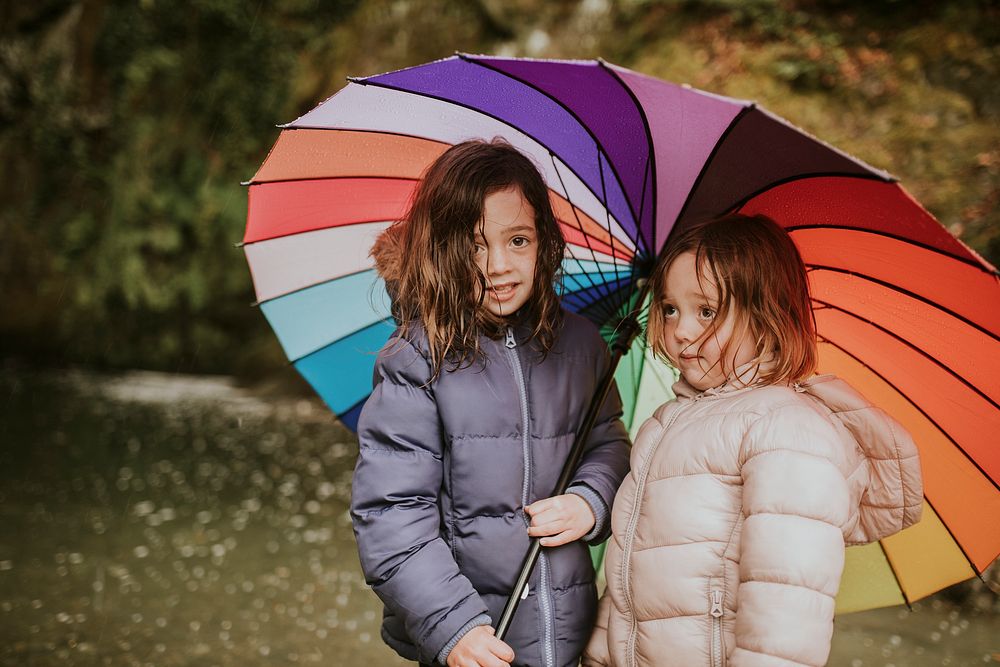 Little girls smiling with an umbrella while on a family trip outdoors portrait