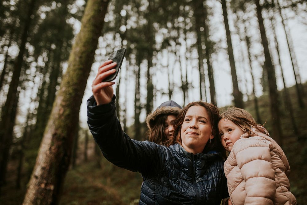 Mother taking selfies with her daughters on a family vacation in the forest