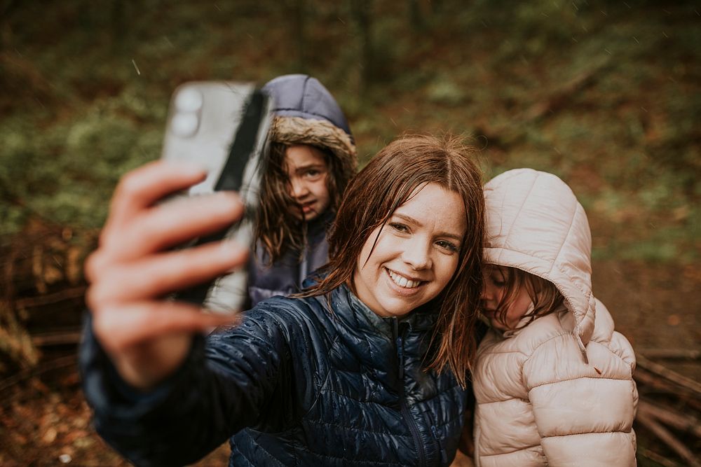 Mother taking selfies with her daughters on a family vacation in the forest