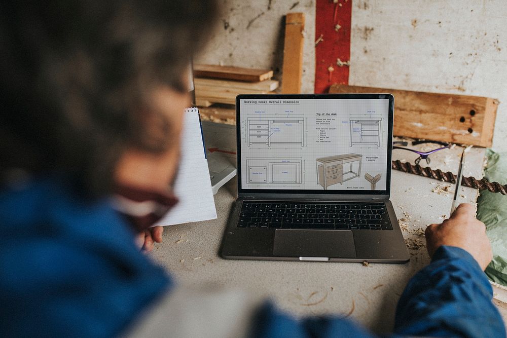 Senior carpenter writing on his notebook with laptop on the desk small business concept 