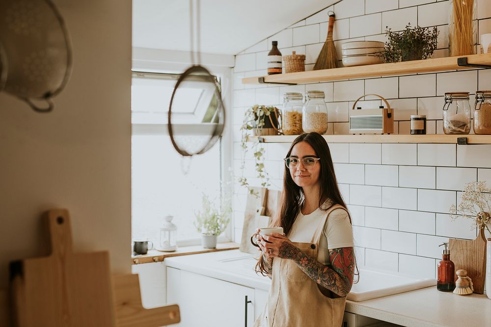 Tattooed woman enjoying tea in her cozy kitchen