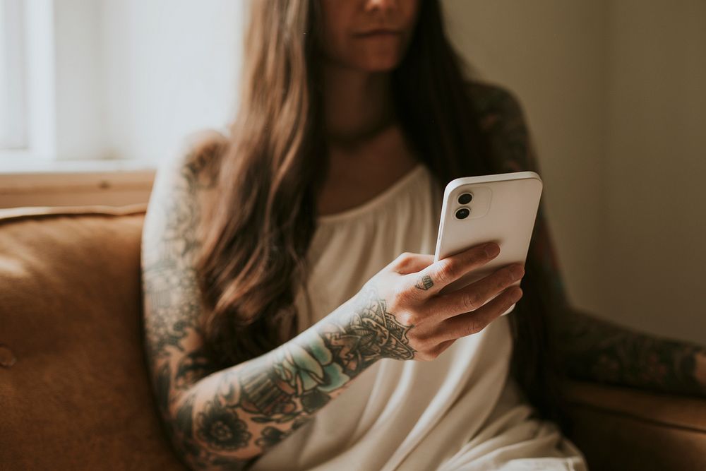 Tattooed woman using her home on the sofa
