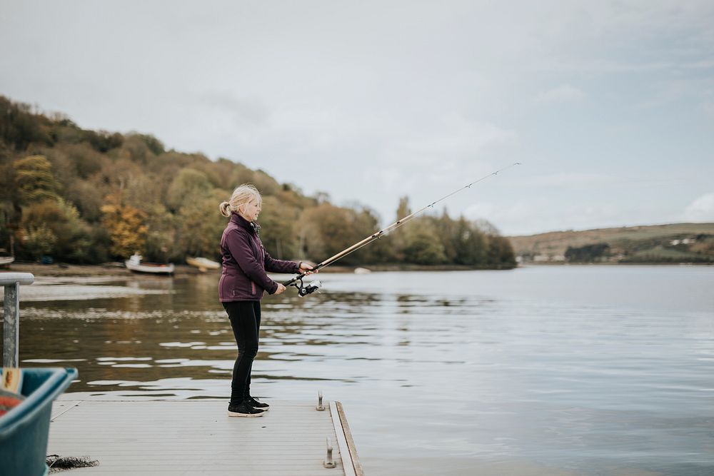 Senior woman enjoying fishing by the lake