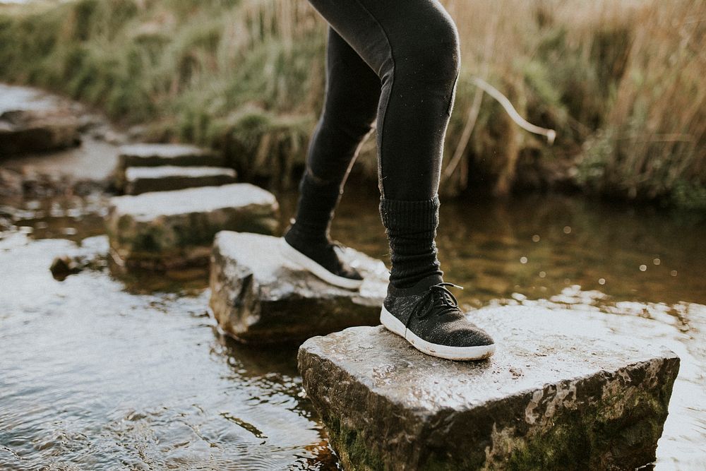 Woman enjoying outdoors adventure crossing the stream 