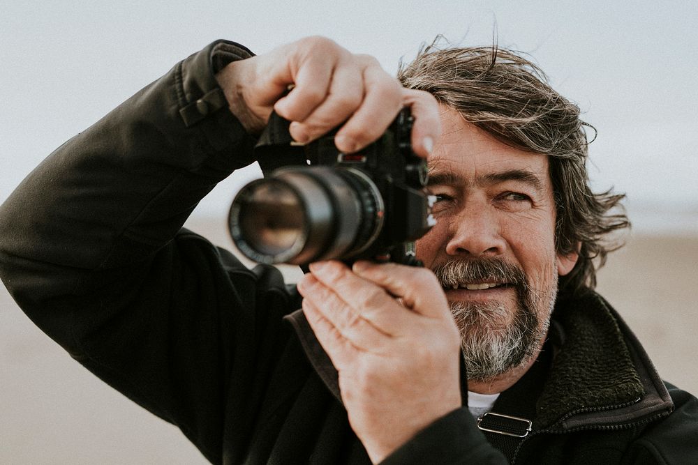 Senior man taking a photo with a camera outdoors