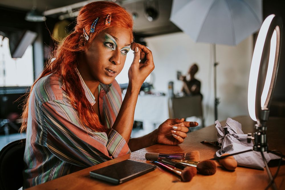 Drag queen in ginger wig putting on makeup