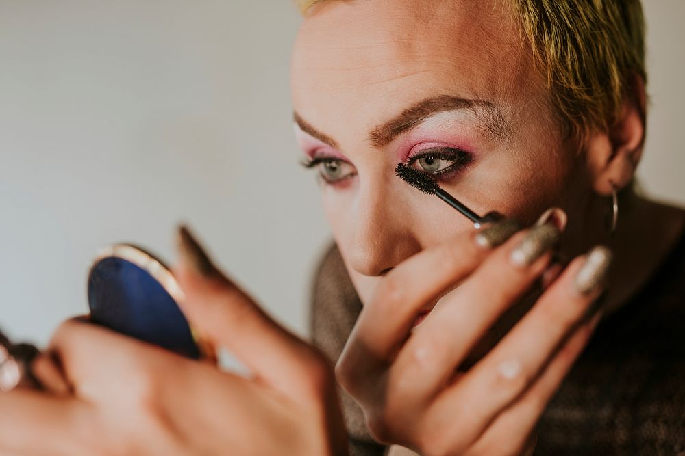 Non-binary person applying mascara, beauty blogger