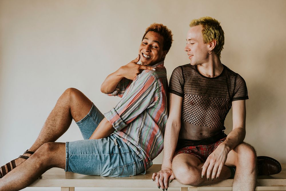 Playful gay couple sitting next to each other, LGBTQ