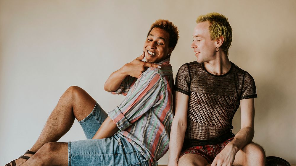 Playful gay couple sitting next to each other, LGBTQ