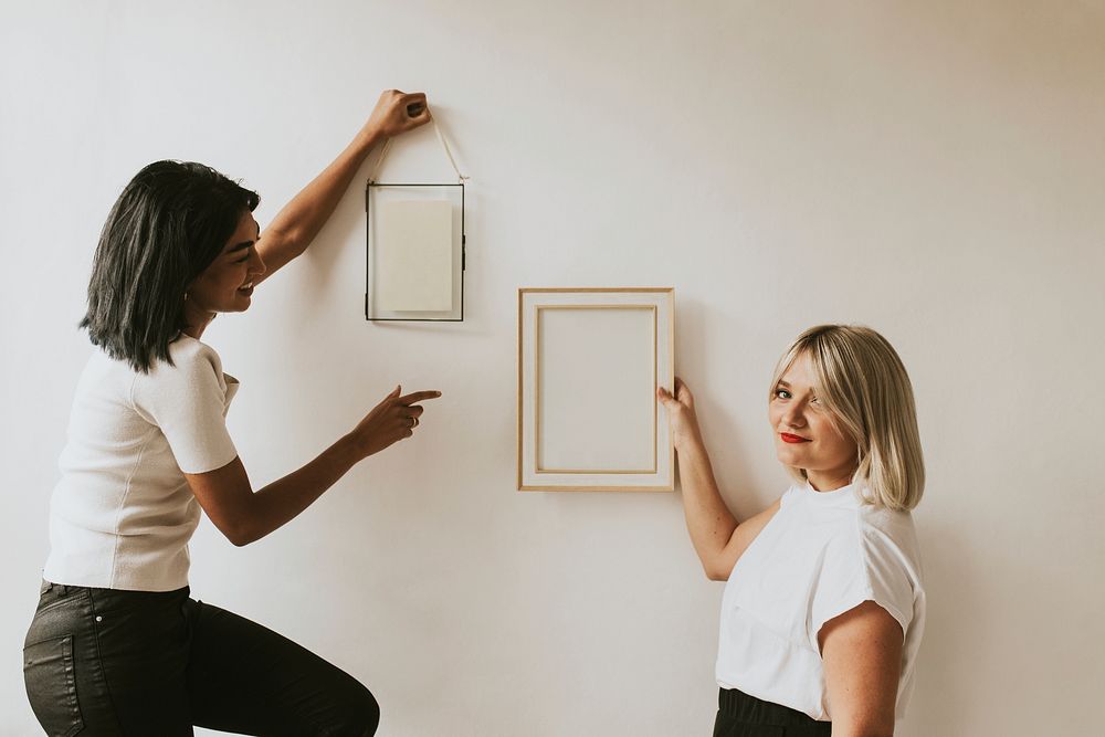 Interior designers styling frames on wall