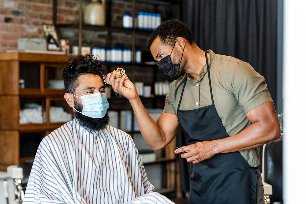 Hairdresser trimming hair of the customer at a barbershop, small business
