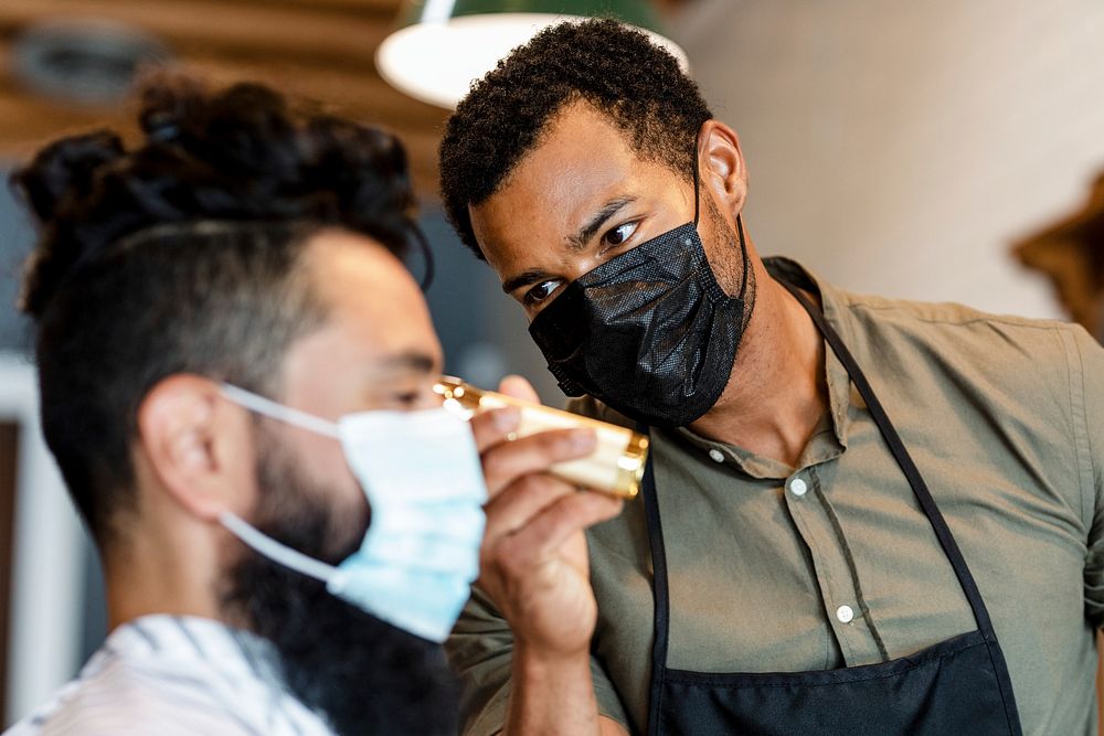 Hair stylist trimming hair of the customer at a barbershop, small business