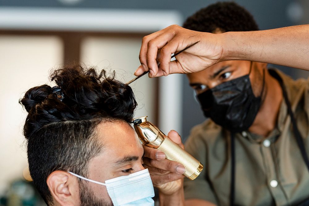 Barber trimming a customer's hair at a barber shop, small business