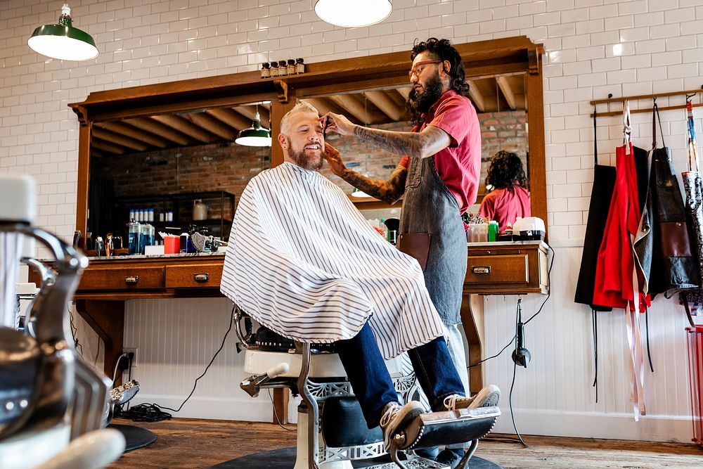 Hairdresser trimming hair of the customer at a barbershop, small business