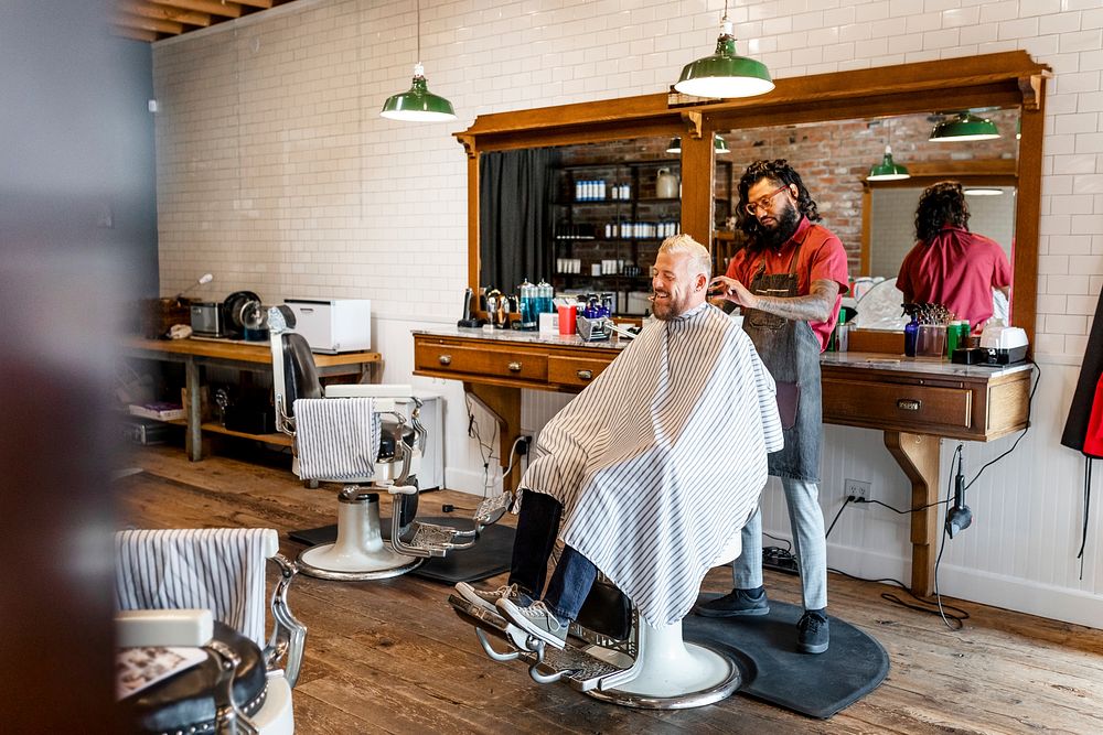 Hair stylist trimming hair of the customer at a barbershop, small business