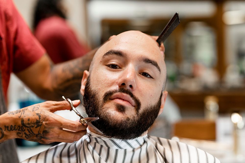 Customer getting a beard trim in a barber shop, small business