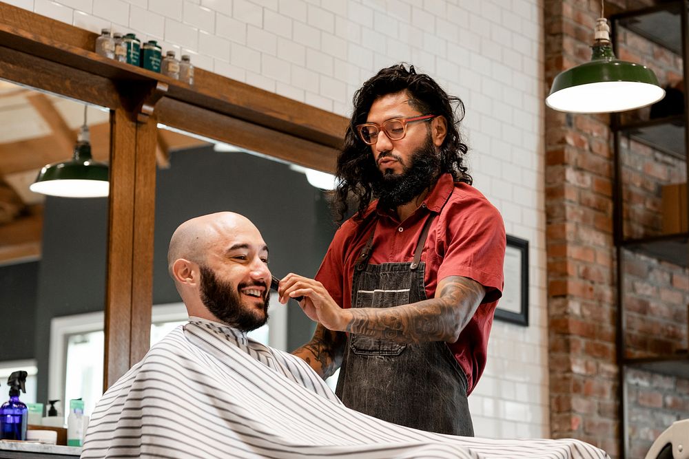 Barber trimming a customer's beard at a barber shop, small business