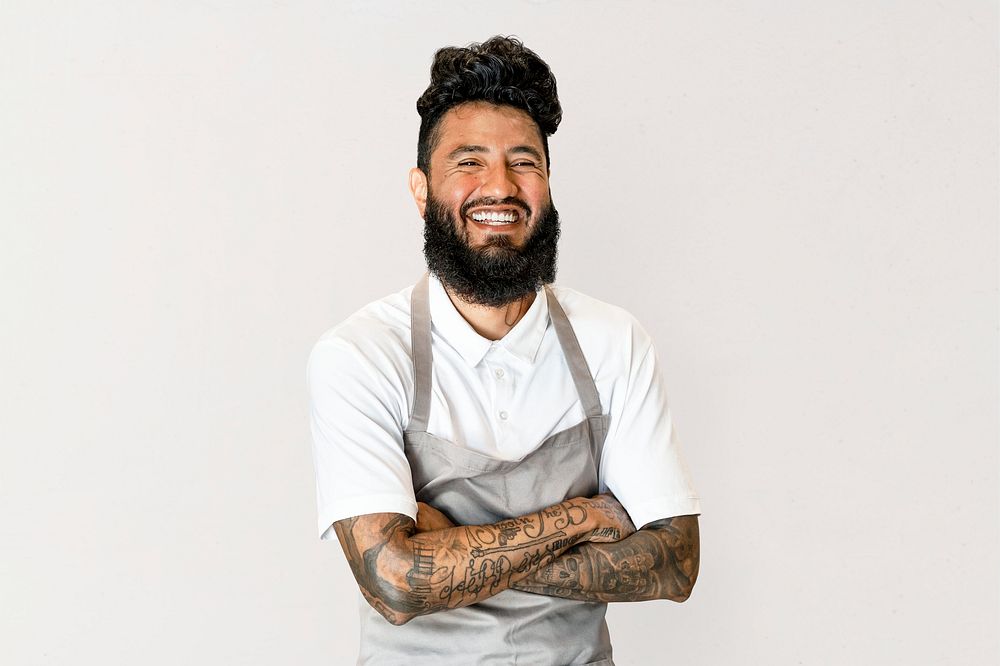Cheerful tattooed man in apron, small business owner, half body