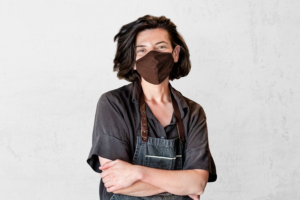 Person in face mask wearing denim apron, small business in the new normal