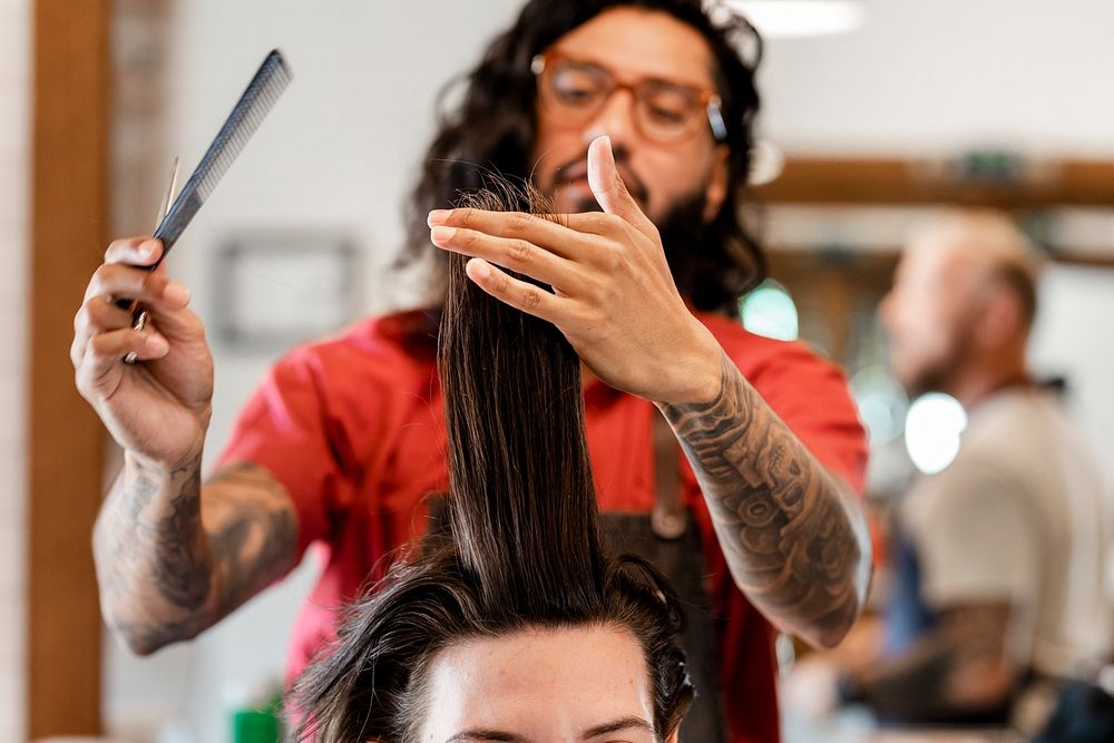 Hairdresser trimming hair of the customer at a barbershop, small business