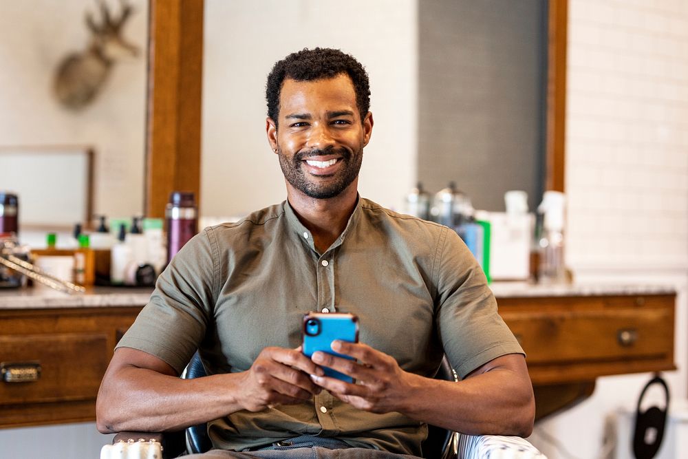 Cheerful man texting in barber shop