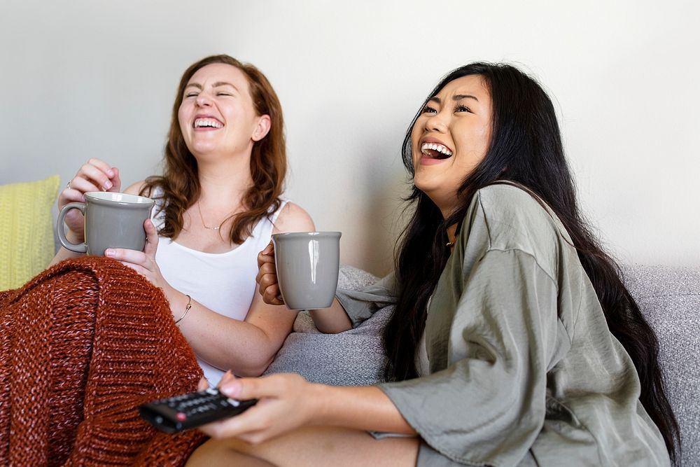 Roommates laughing out loud on the sofa