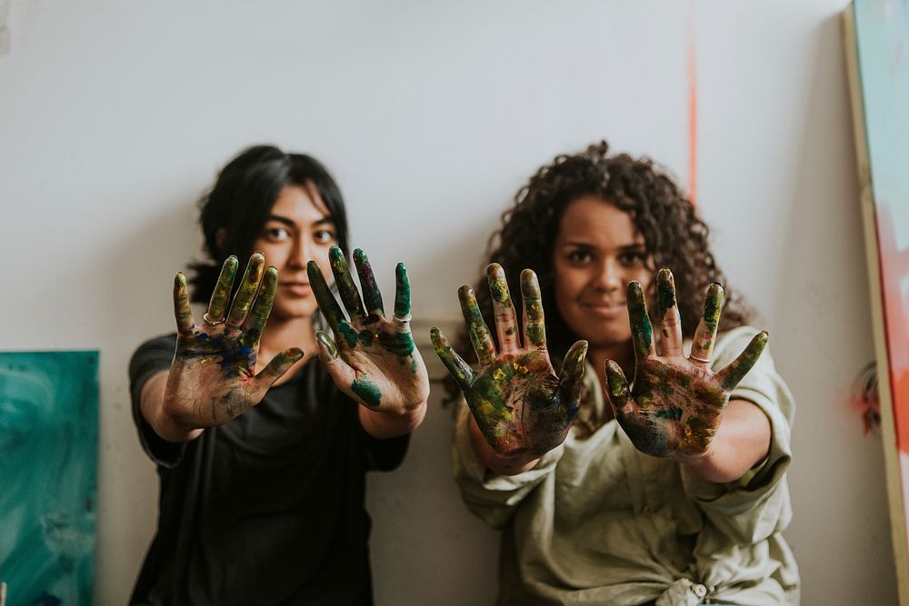 Female artist friends showing their paint covered hands