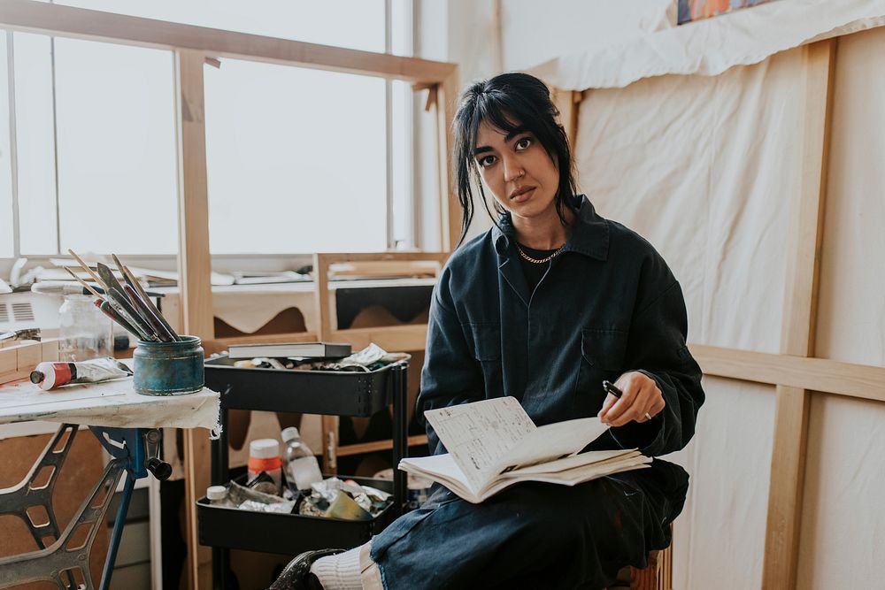 Woman artist reading and studying in her studio 