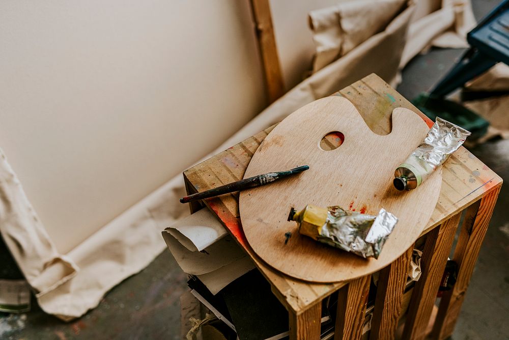 Artist's tools including color palette and paint brush on a wooden table 