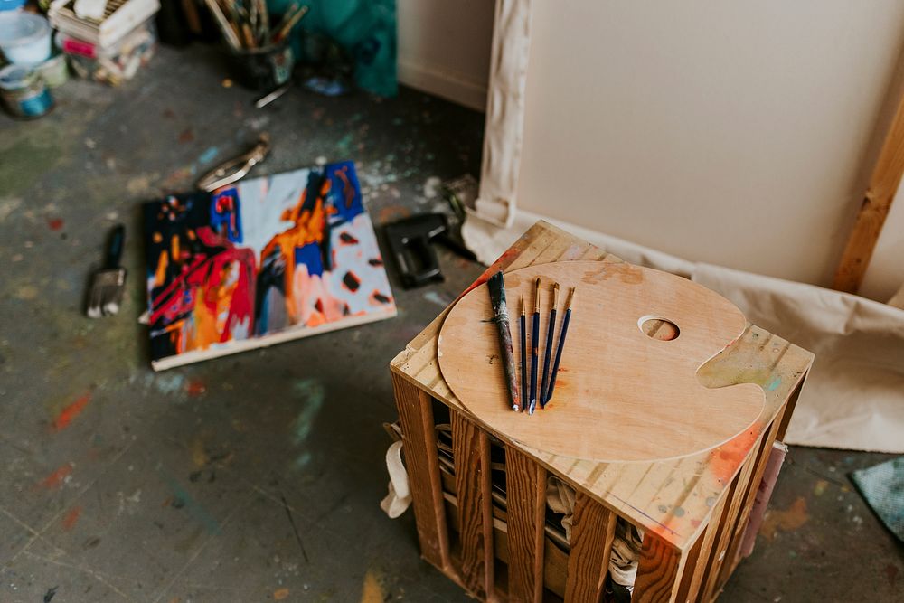 Artist's tools including color palette and paint brush on a wooden table 