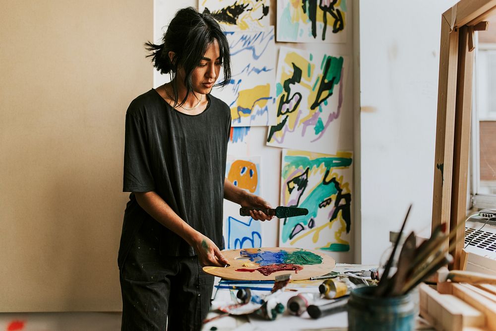 Woman artist mixing paint on a color palette 