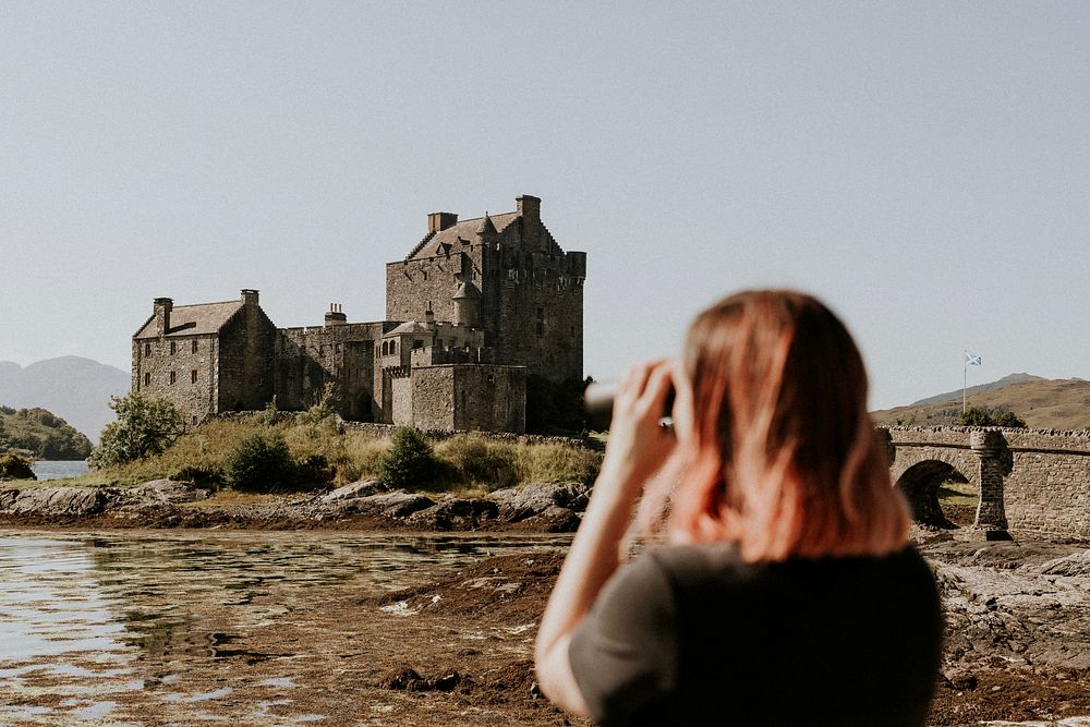 Scottish castle by a pond, tourist taking photos of the scene